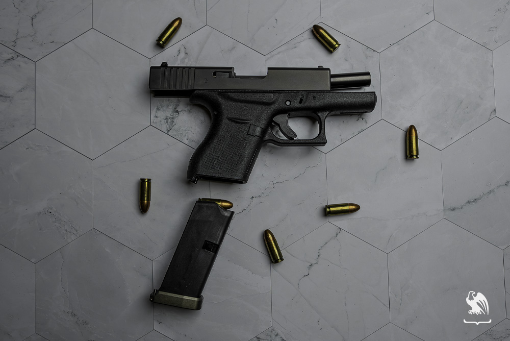 Handgun disassemble laying on surface with bullets around it
