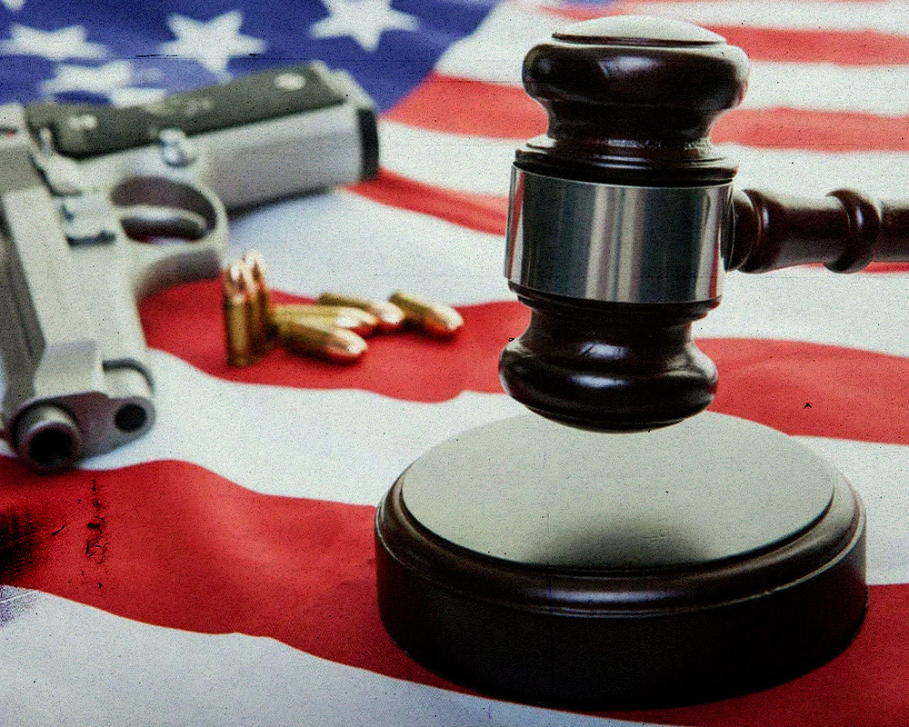 A gavel, a handgun and bullets on top of an American flag. 