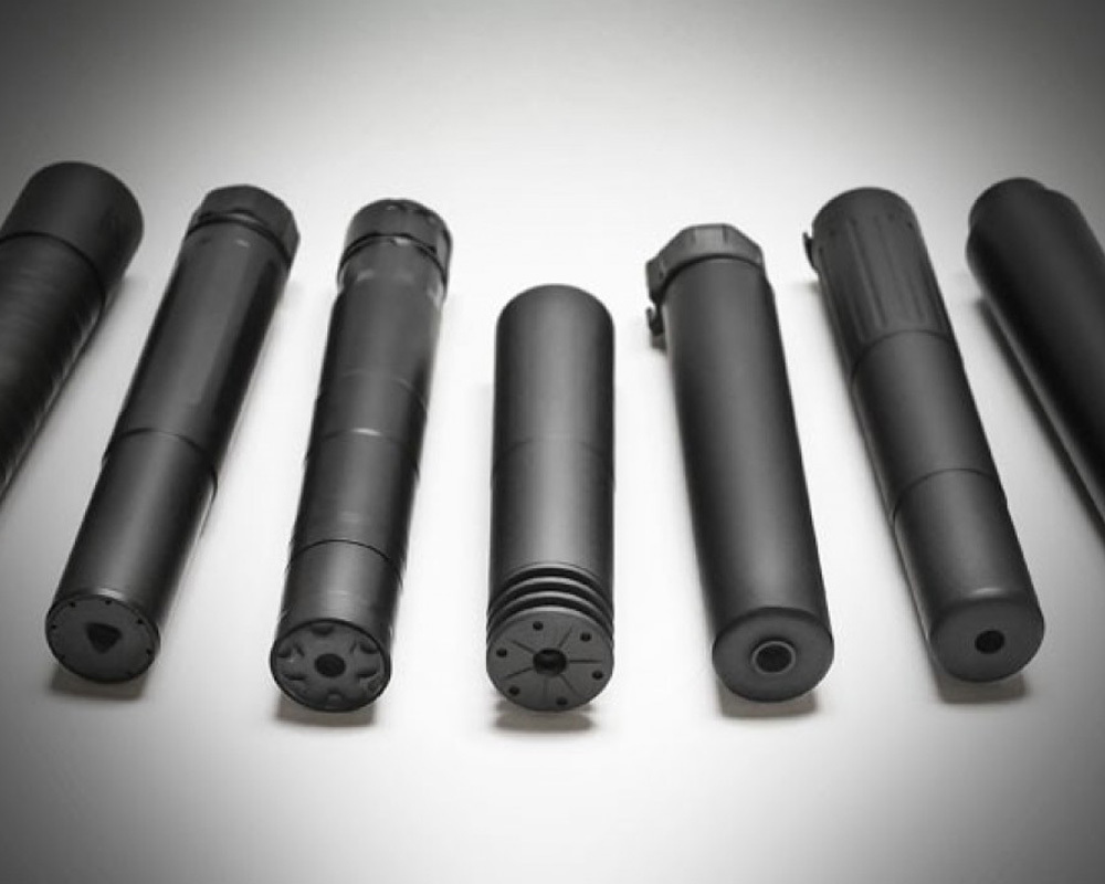 Different silencers and suppressors laying on a table.