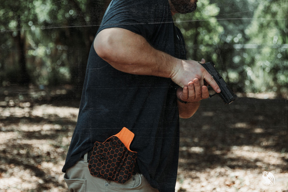 Larger Build bearded man in casual clothing aiming his handgun in a shooting stance, wearing a Vedder LightDraw OWB Kydex holster for open carry or range use.