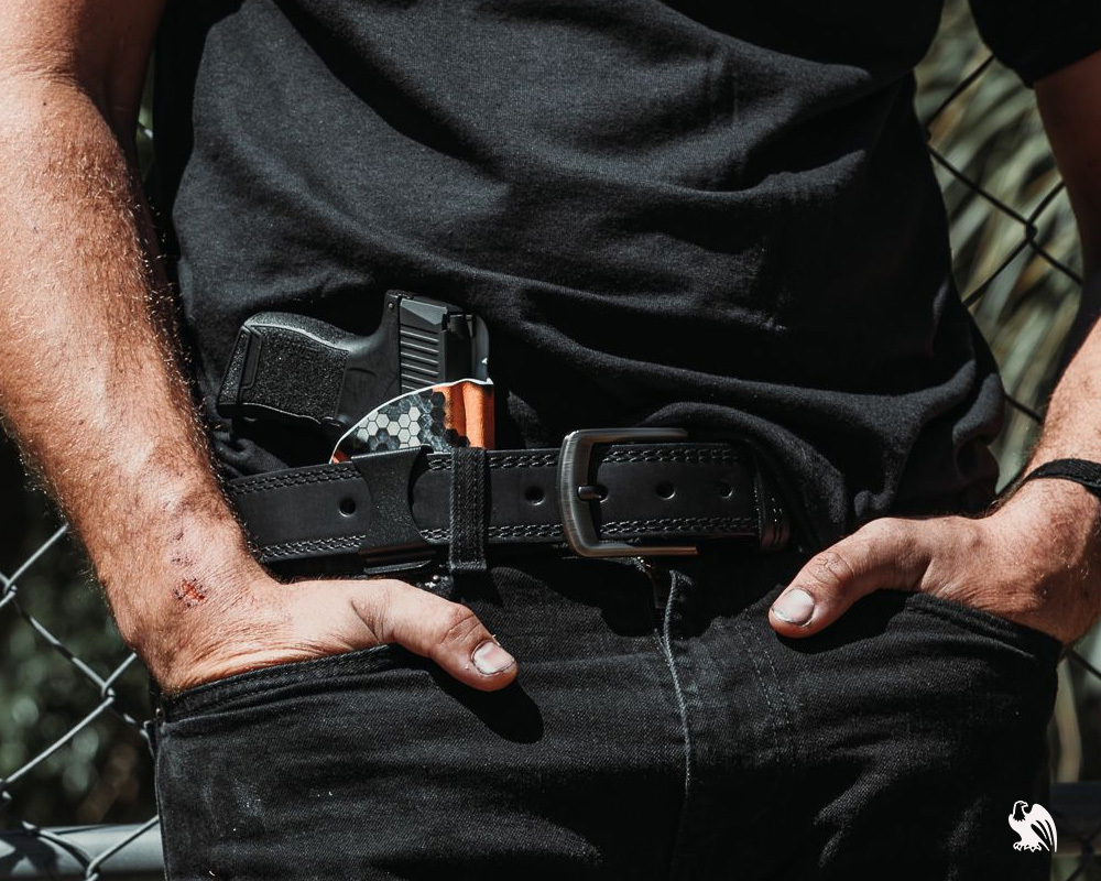 Man wearing a Vedder IWB Kydex holster with a concealed pistol, secured by a sturdy black leather gun belt for everyday carry.