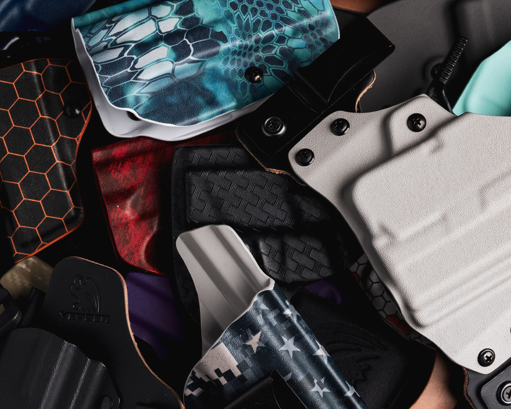 A variety of Vedder Holsters in different colors, textures, and custom prints, showcasing the range of Kydex material and personalization options available.