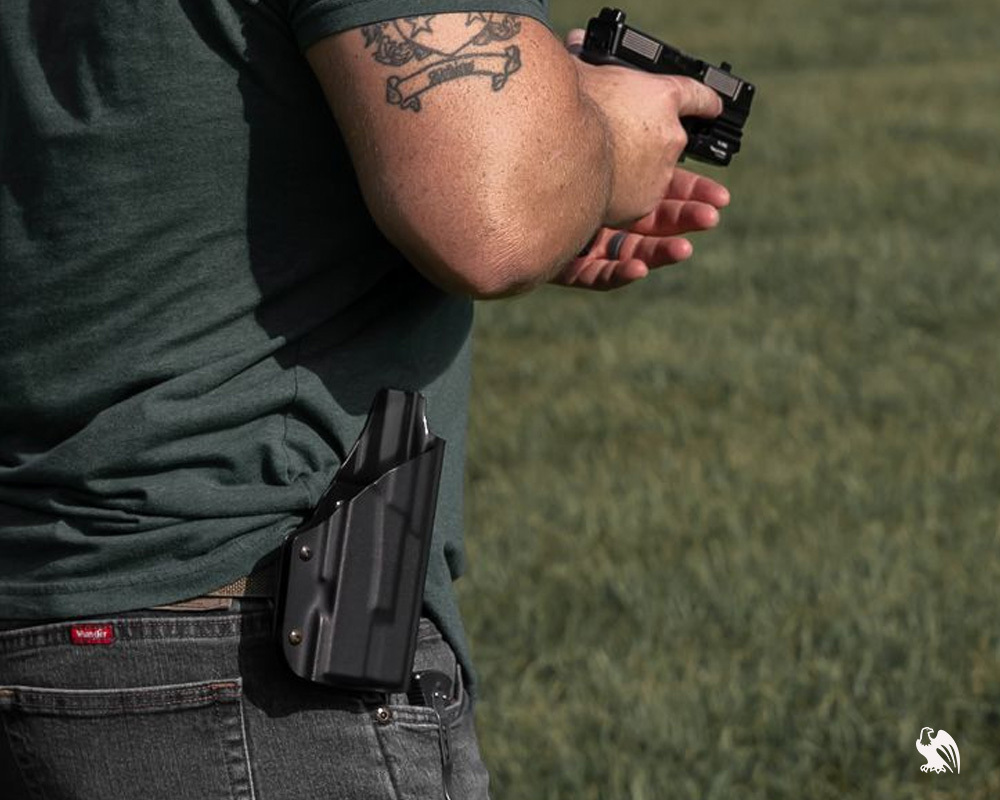 A person practices drawing from a Vedder Holsters OWB (outside-the-waistband) holster in a training environment, showcasing secure retention and accessibility.