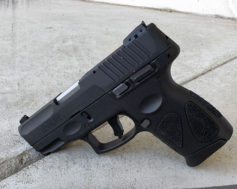 Taurus G2C 9mm pistol standing upright on a concrete surface outdoors, showcasing its compact frame and textured grip.