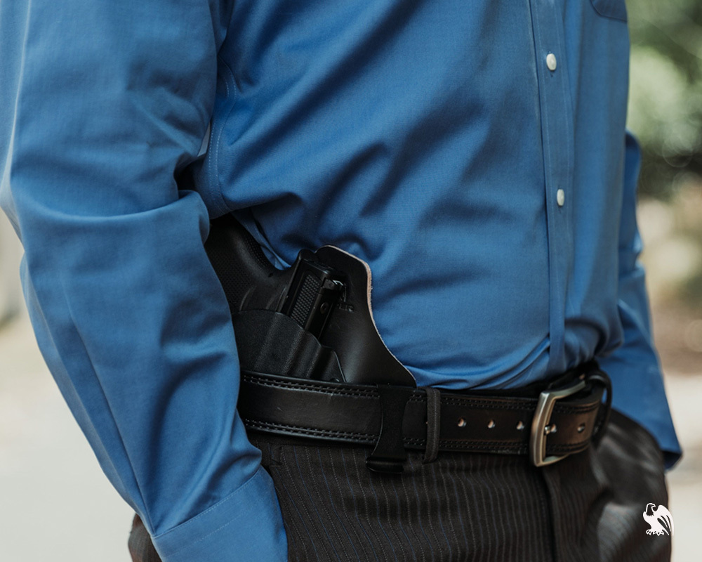 Man wearing a blue shirt and black pants with a leather belt, carrying a Kimber Micro 9 in a Vedder ComfortTuck IWB hybrid holster.