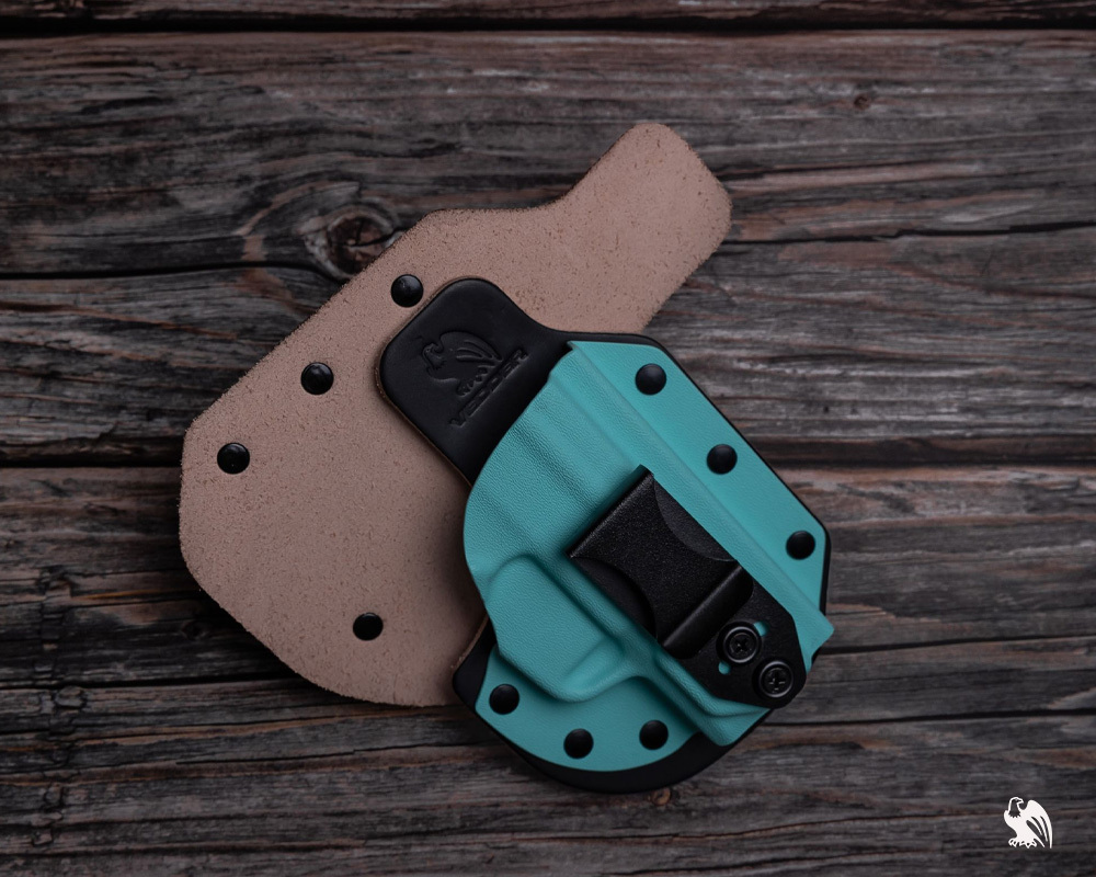 Two Vedder RapidTuck IWB holsters for the Kimber Micro 9 on a wood surface, one teal holster facing forward and the other laid flat showing the back side.