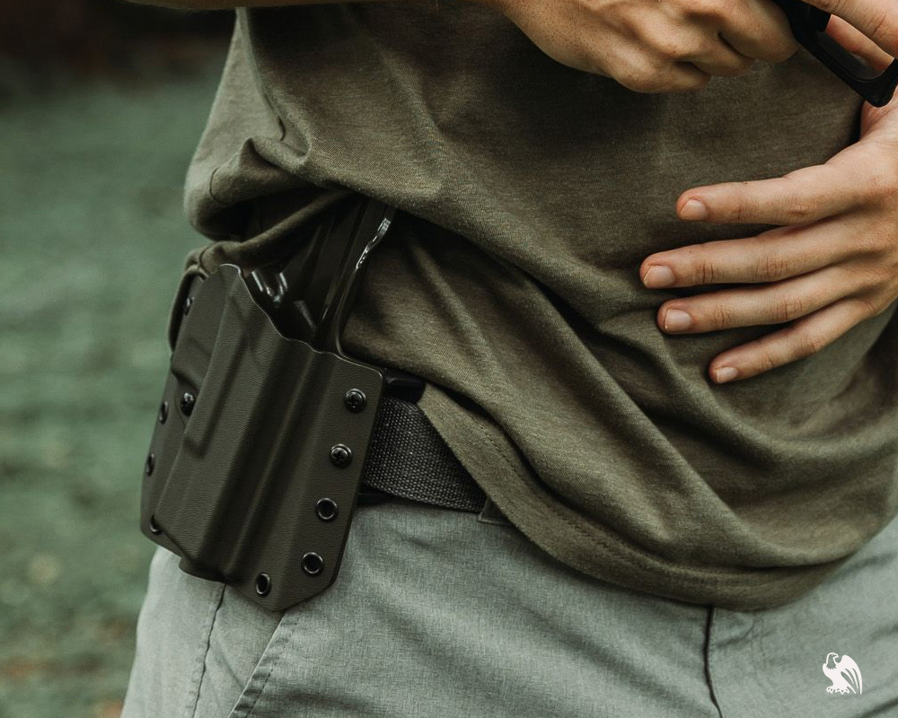 Man wearing a green shirt and grey shorts with a black belt, carrying a Kimber Micro 9 in a Vedder LightDraw OWB holster.
