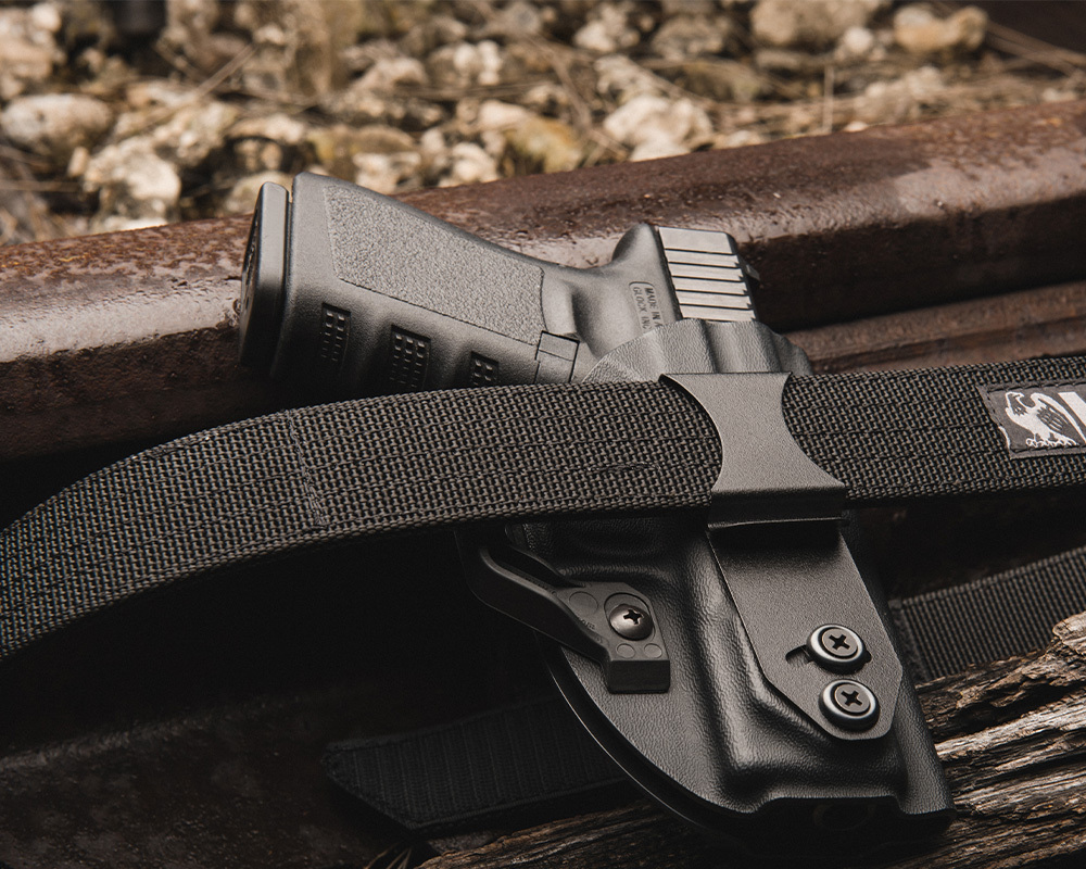 Close-up of a Glock pistol secured in a black Kydex OWB holster attached to a durable nylon gun belt, showcasing secure firearm retention and everyday carry reliability.