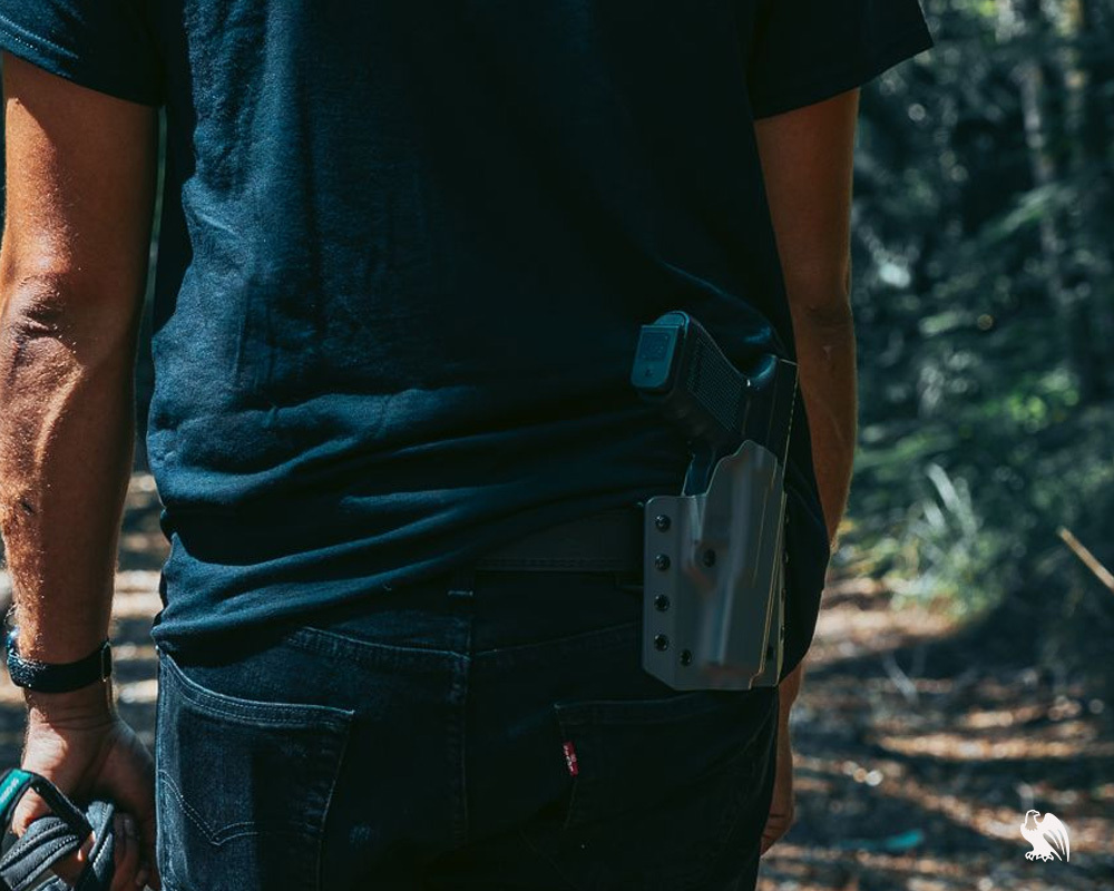 Man carrying his Beretta M9 on a LightDraw OWB Holster on the back position from Vedder Holsters. 