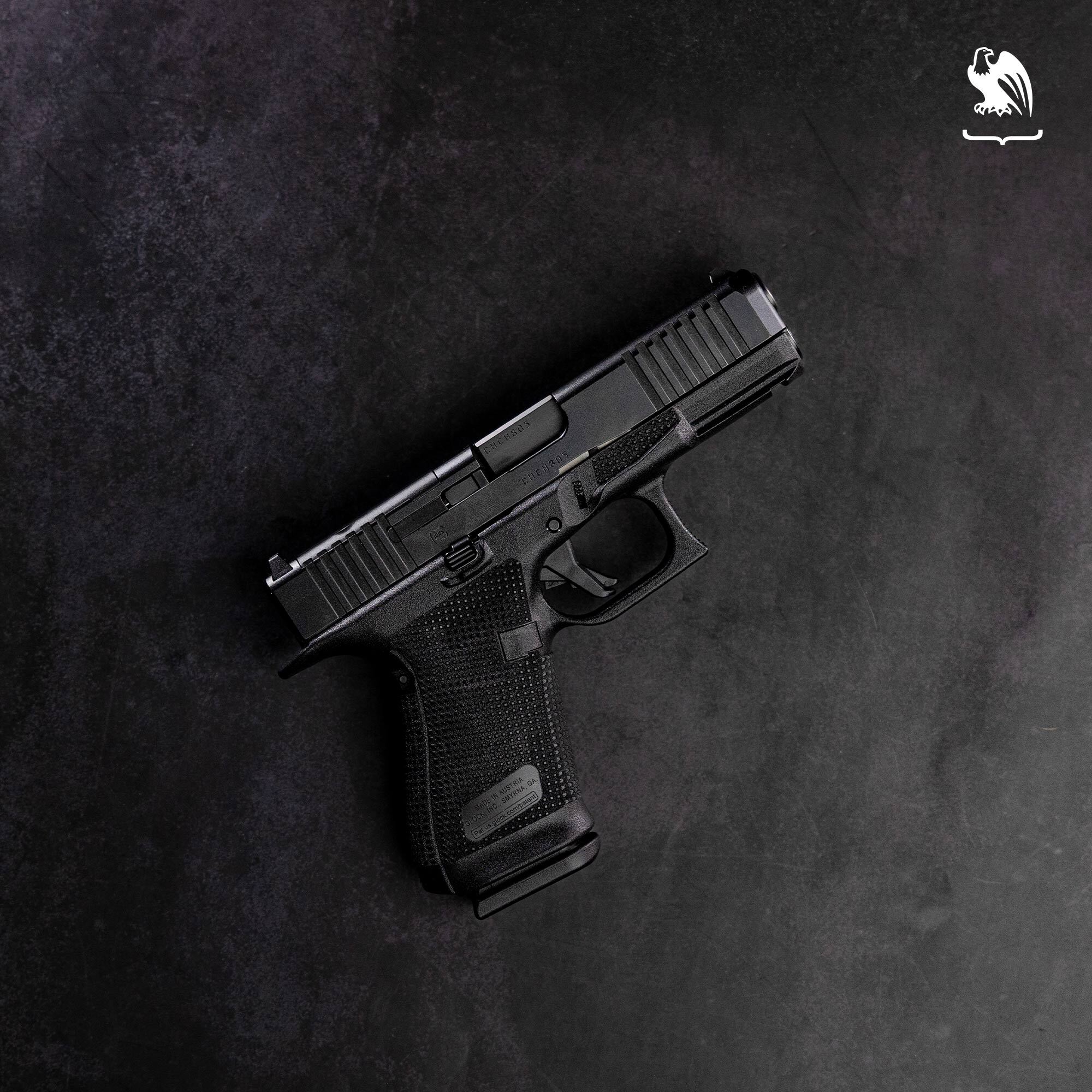 Glock 19 semi-automatic pistol in matte black finish displayed on dark concrete background