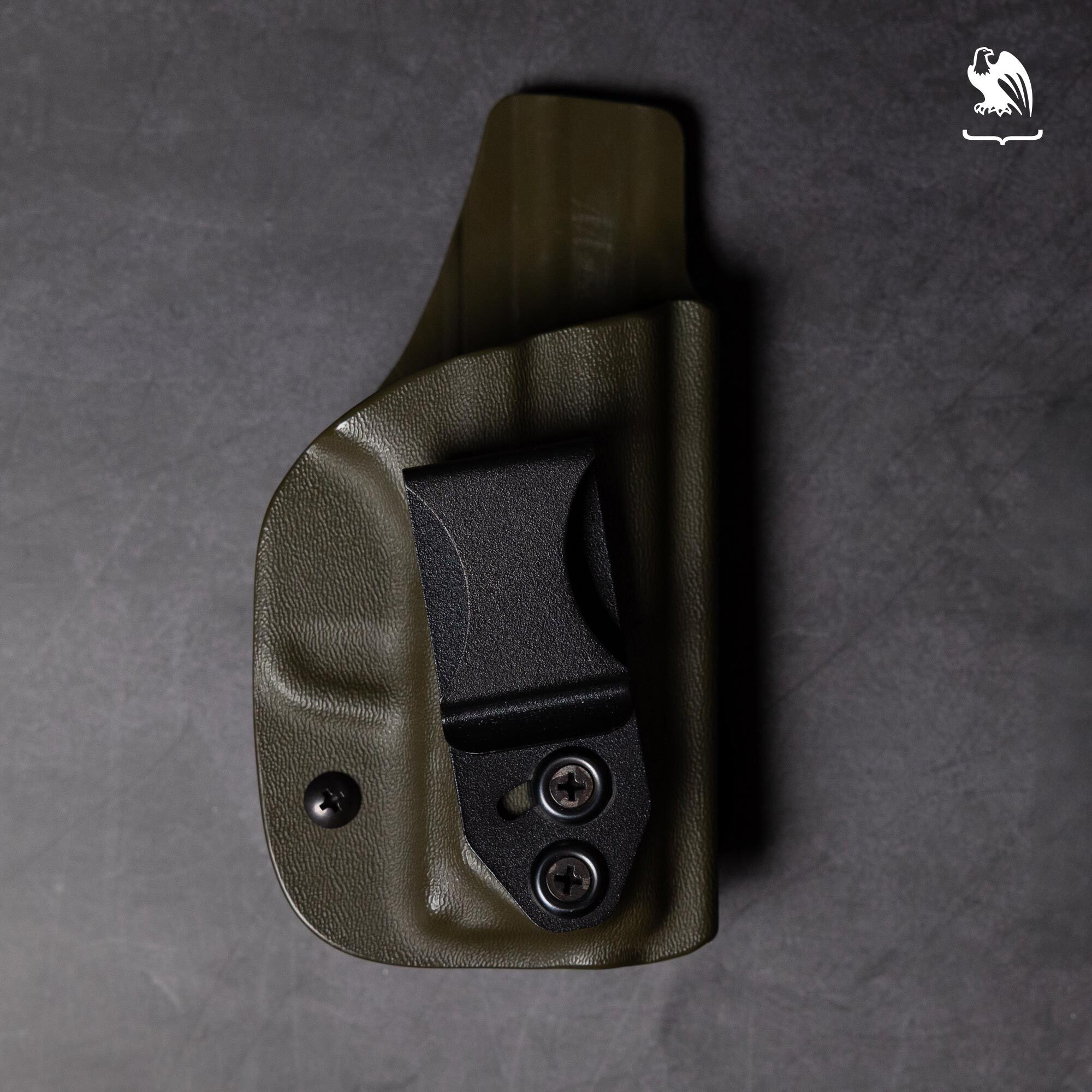 Olive drab green Kydex IWB holster with adjustable cant clip and dual retention screws on a dark gray concrete background &mdash; inside-the-waistband holster for Canik pistols in OD green.