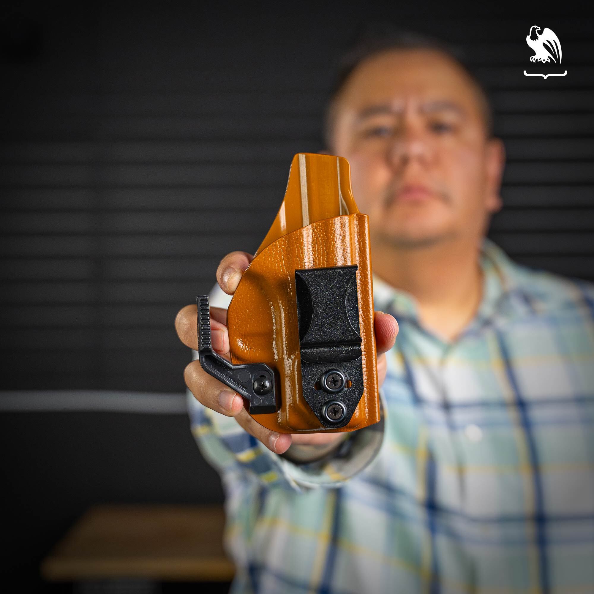 Brown Vedder Holsters LightTuck A man in a plaid shirt holds a brown Vedder Holsters LightTuck in front of his face.
