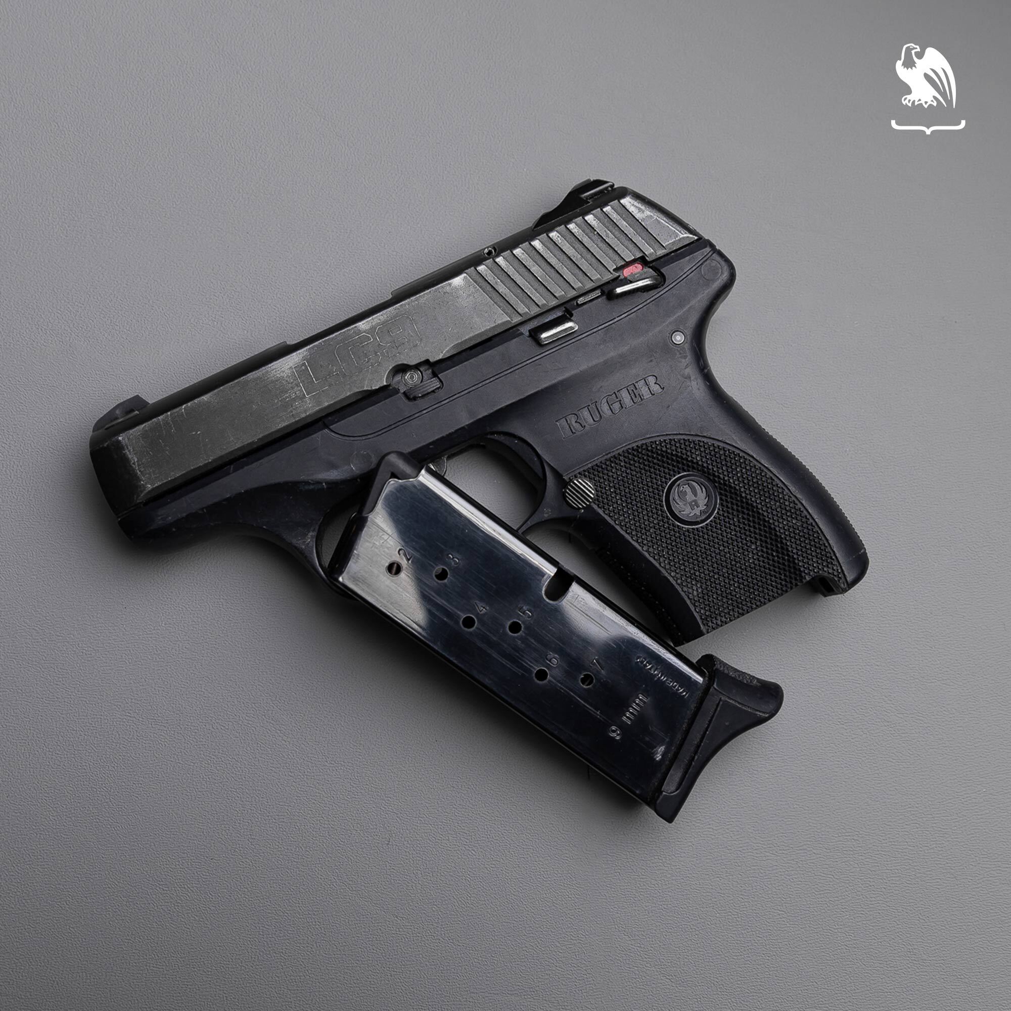 Ruger LC9 9mm pistol with detached magazine on gray background