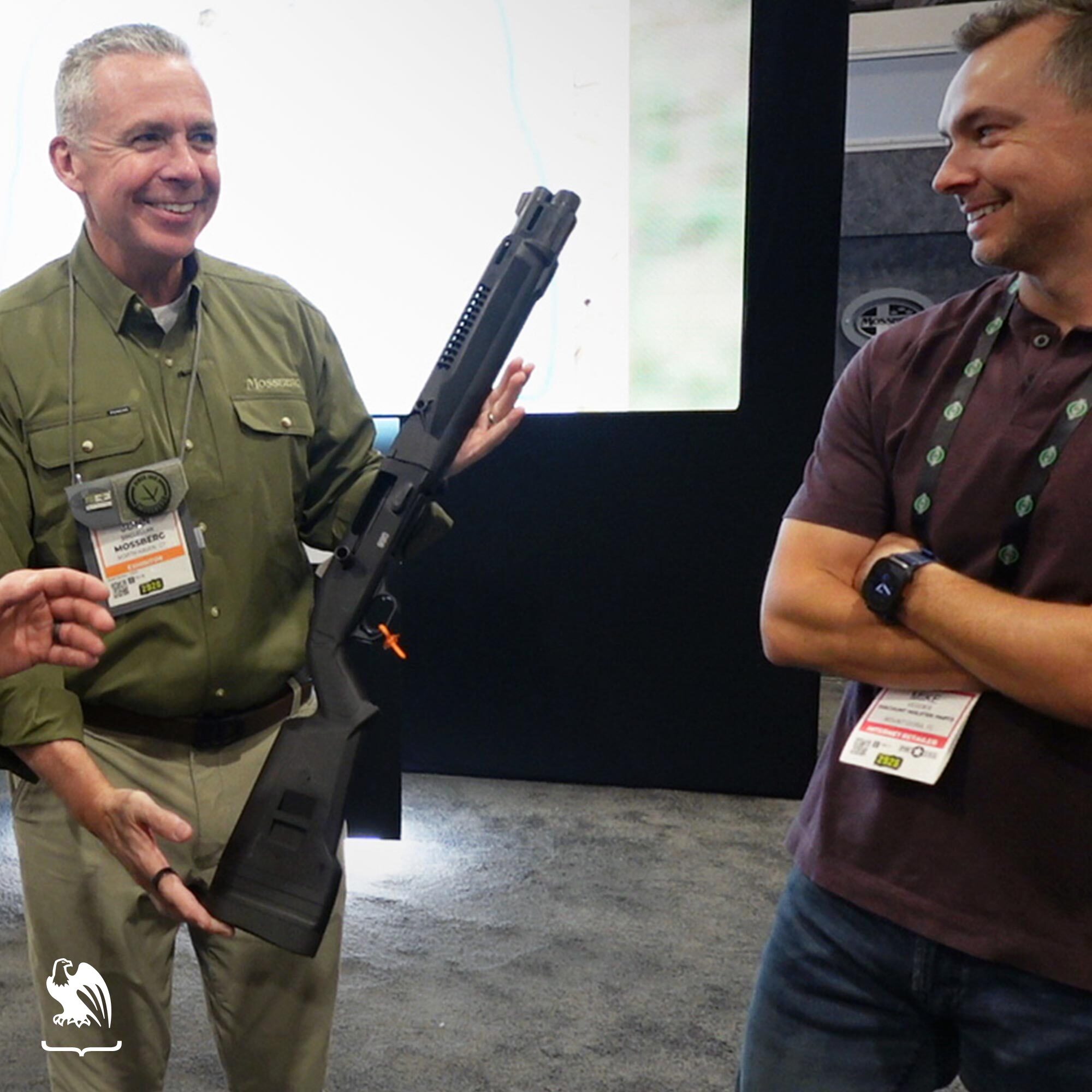 Industry representatives discussing a tactical shotgun during a live product demonstration at the SHOT Show 2026 trade event.