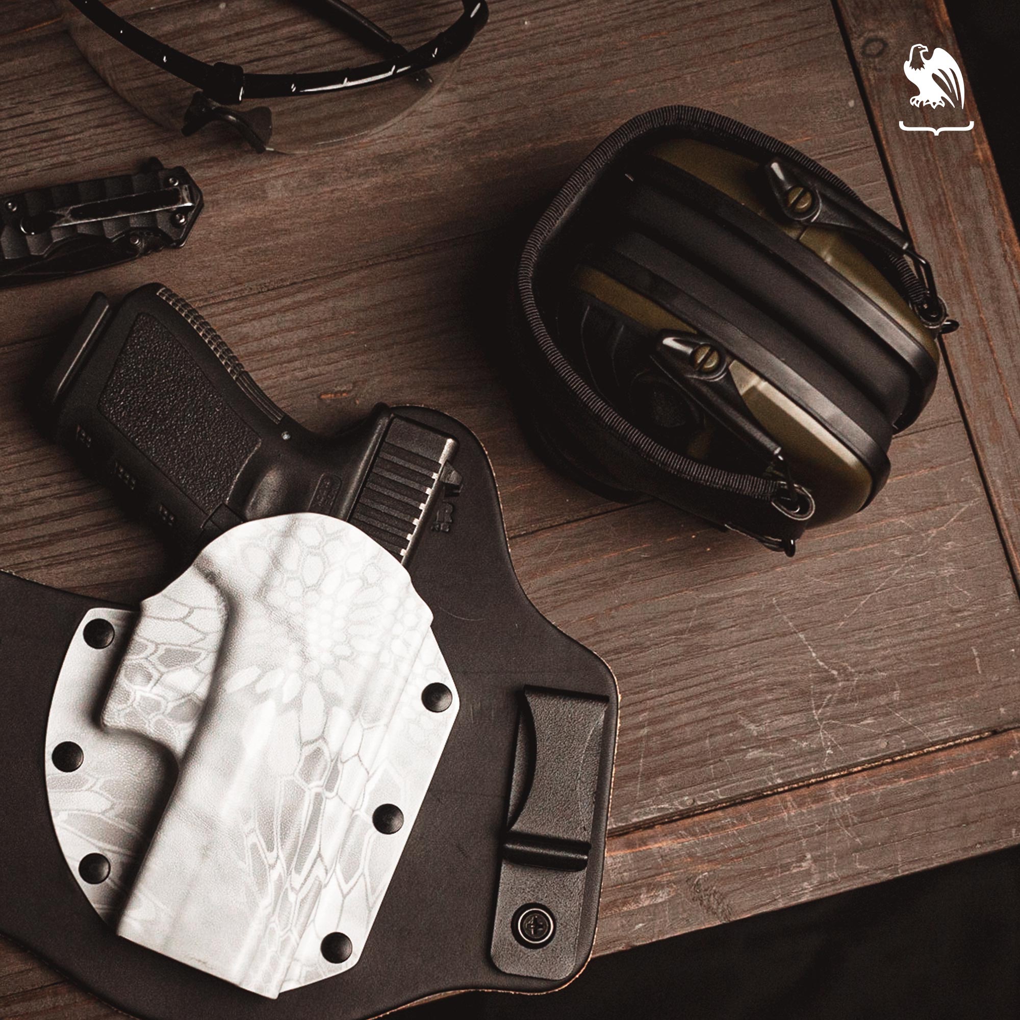 A table filled with items you need when you go shooting as ear protection, a Vedder Holster, your handgun, protective eyewear and a pocket knife.