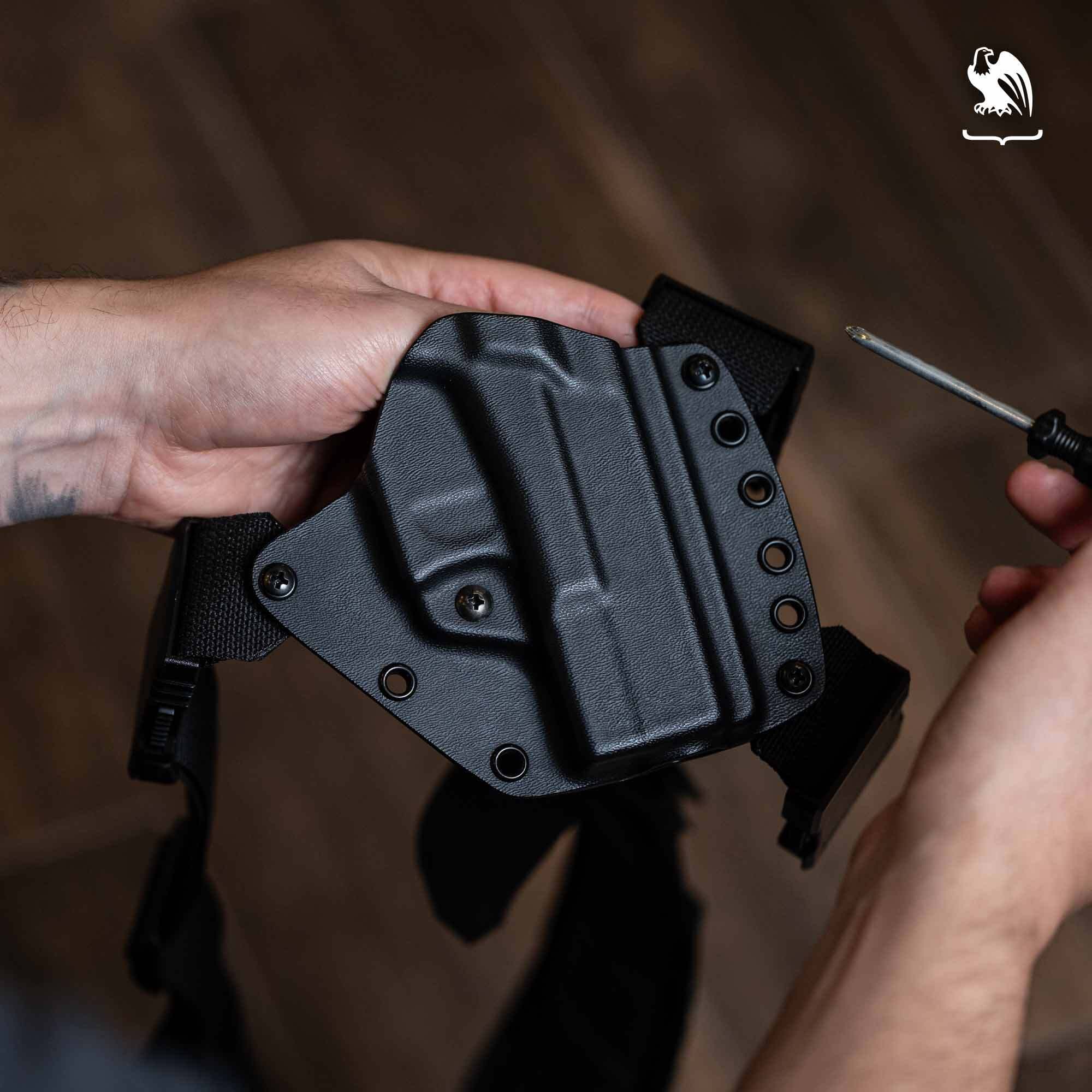 Hands adjusting a Vedder Holsters Kydex chest holster with screwdriver for custom fit.