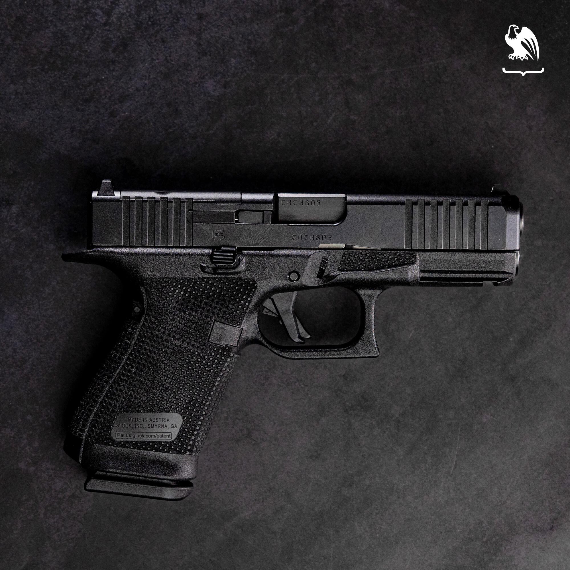 Side profile of a custom black Glock pistol with professional frame stippling, front slide serrations, and an undercut trigger guard.