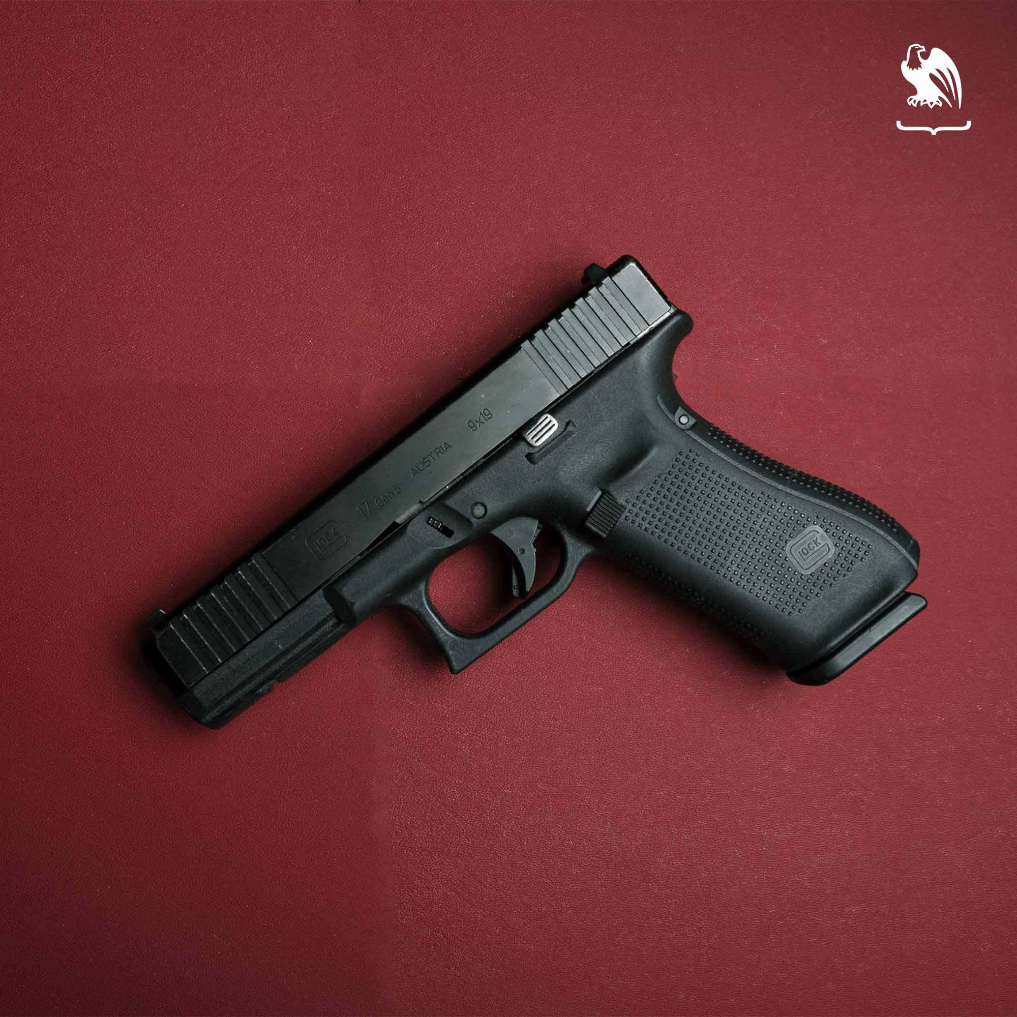 Glock 17 9mm semi-automatic handgun with black polymer frame and textured grip photographed on a red background.