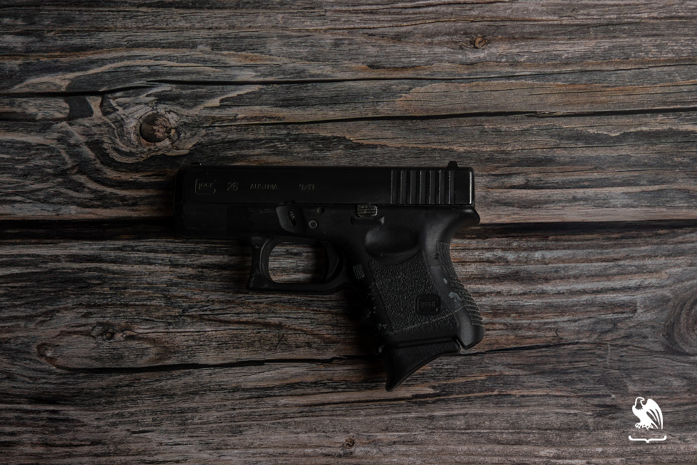 Glock 26 handgun laying on a wood table