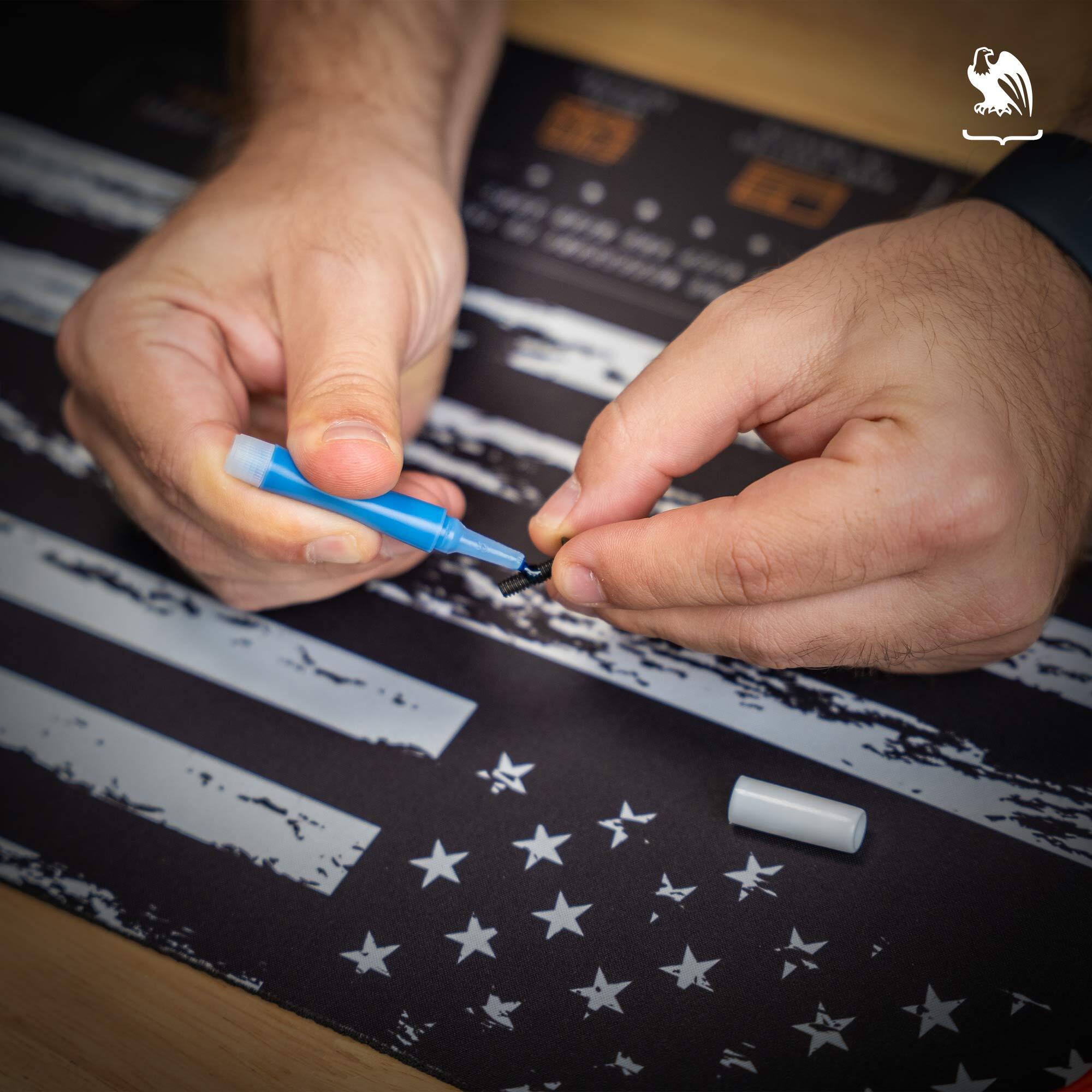 Threadlocker A man puts a dab of blue threadlocker on a screw while using a Vedder Holsters Gun Cleaning Mat