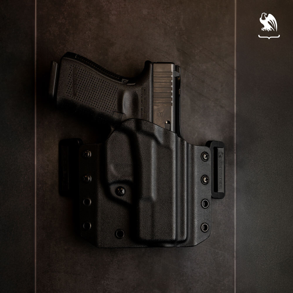 A Glock 19 laying on a black table holstered inside a LightDraw OWB Holster with OWB standard clips.