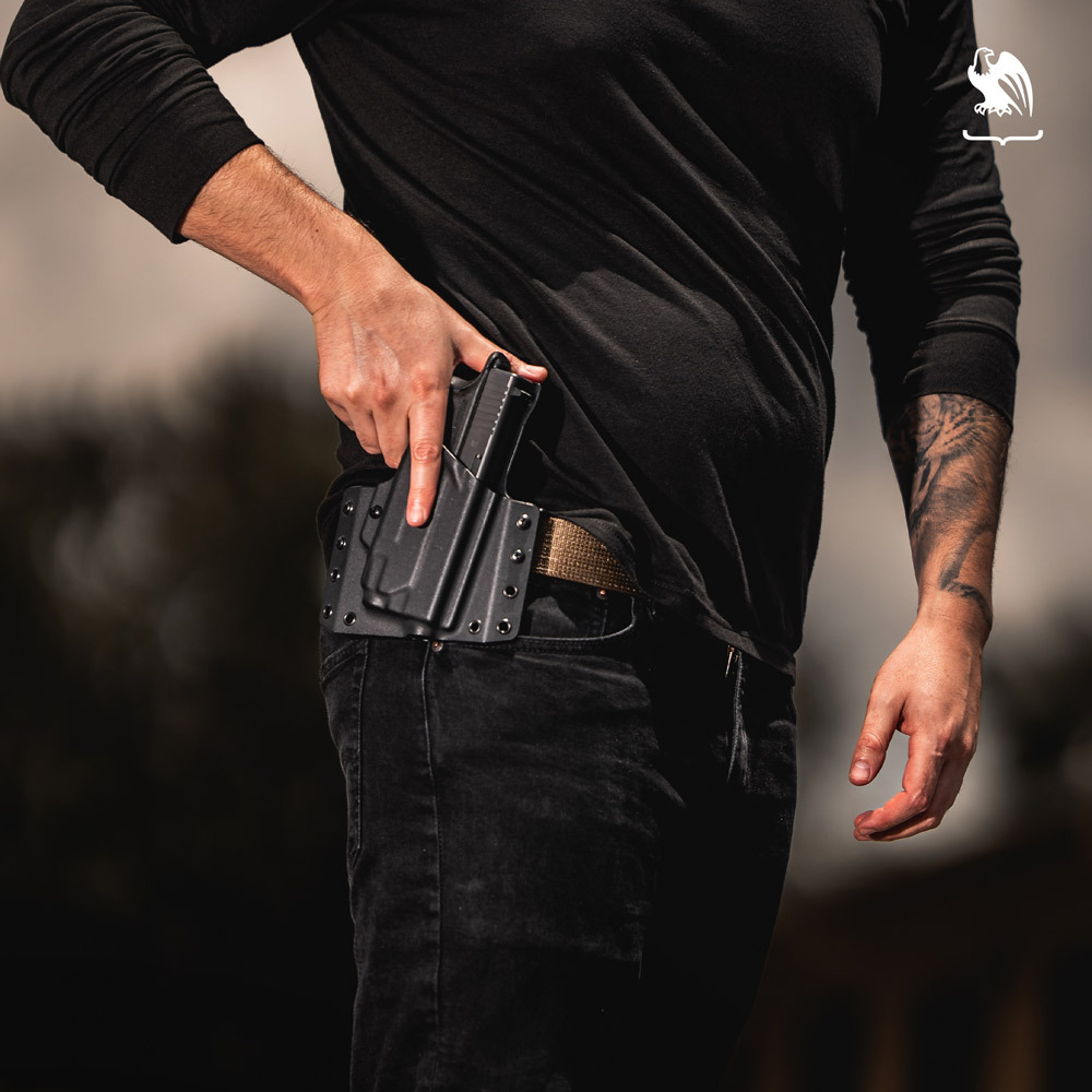Man outdoors wearing all black wearing a LightDraw OWB Kydex Holsters ready to draw his M1911 handgun.