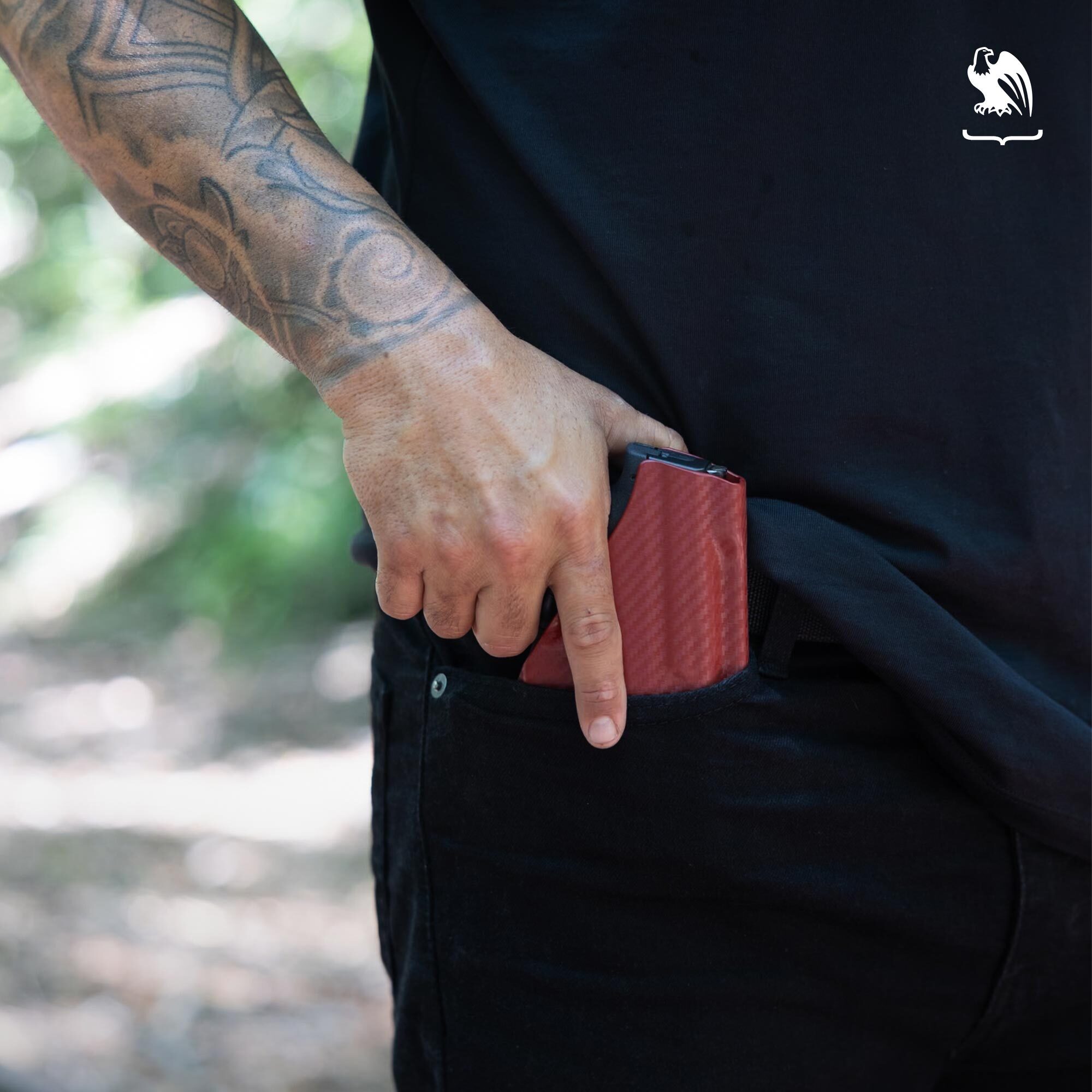 Man with tattoos holding his handgun ready to draw it from his pocket holster that was hidden on his front right pocket.