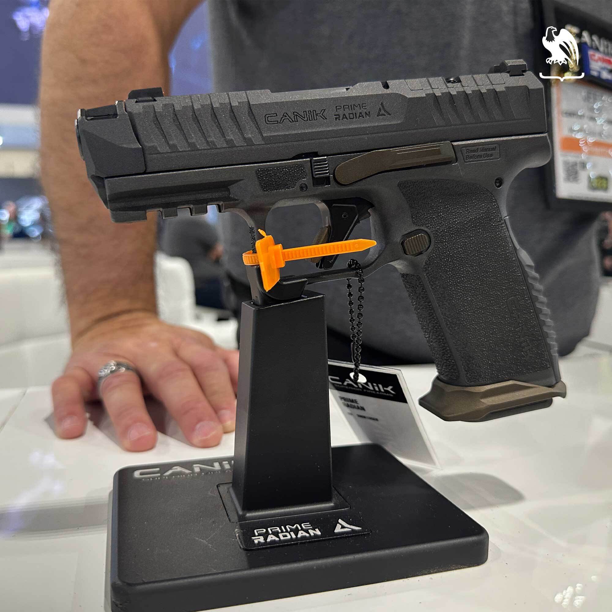 Canik Prime Radian 9mm pistol displayed on a standRadian Specs with an orange chamber safety flag during a trade show demo.