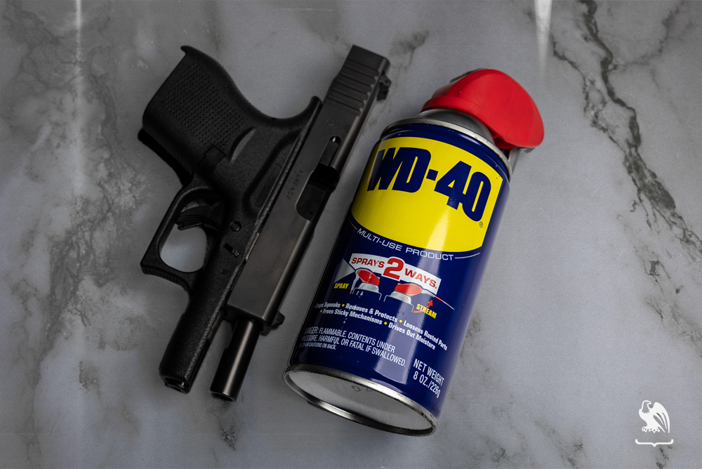 Handgun next to a WD-40 laying on a marble table