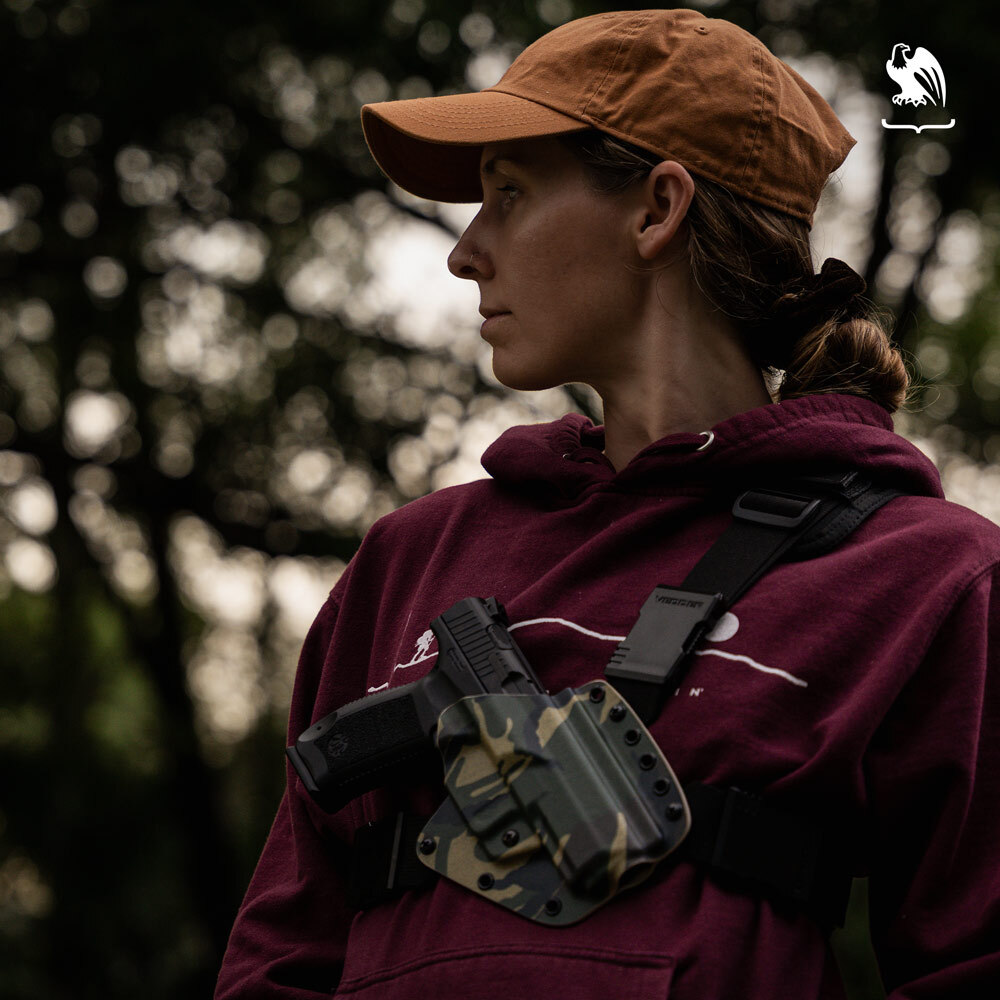 Woman wearing a Evertrek chest holster over a red hoodie while she is outdoors.