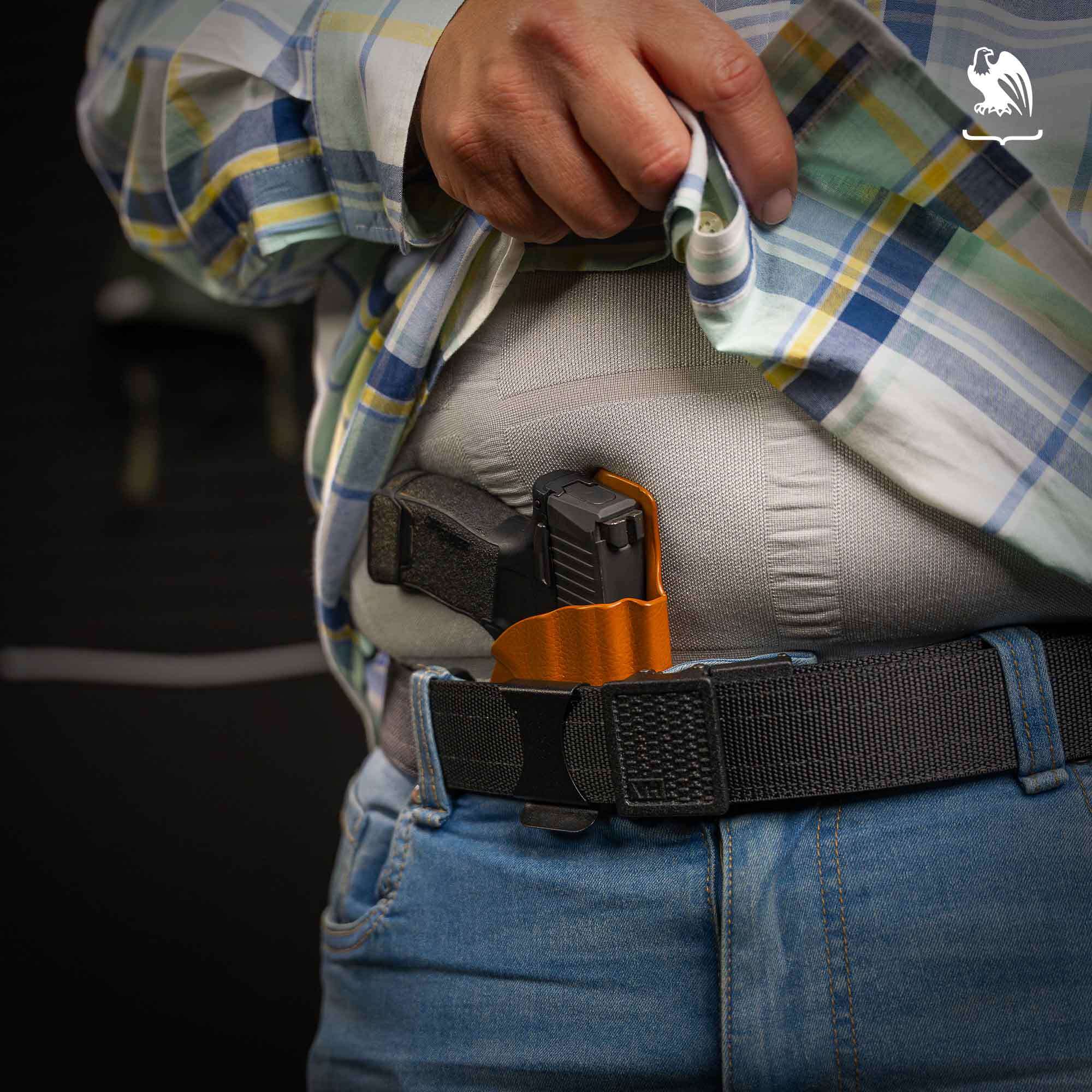 A heavyset man carries a pistol in an orange Vedder Holsters LightTuck in the appendix carry position.