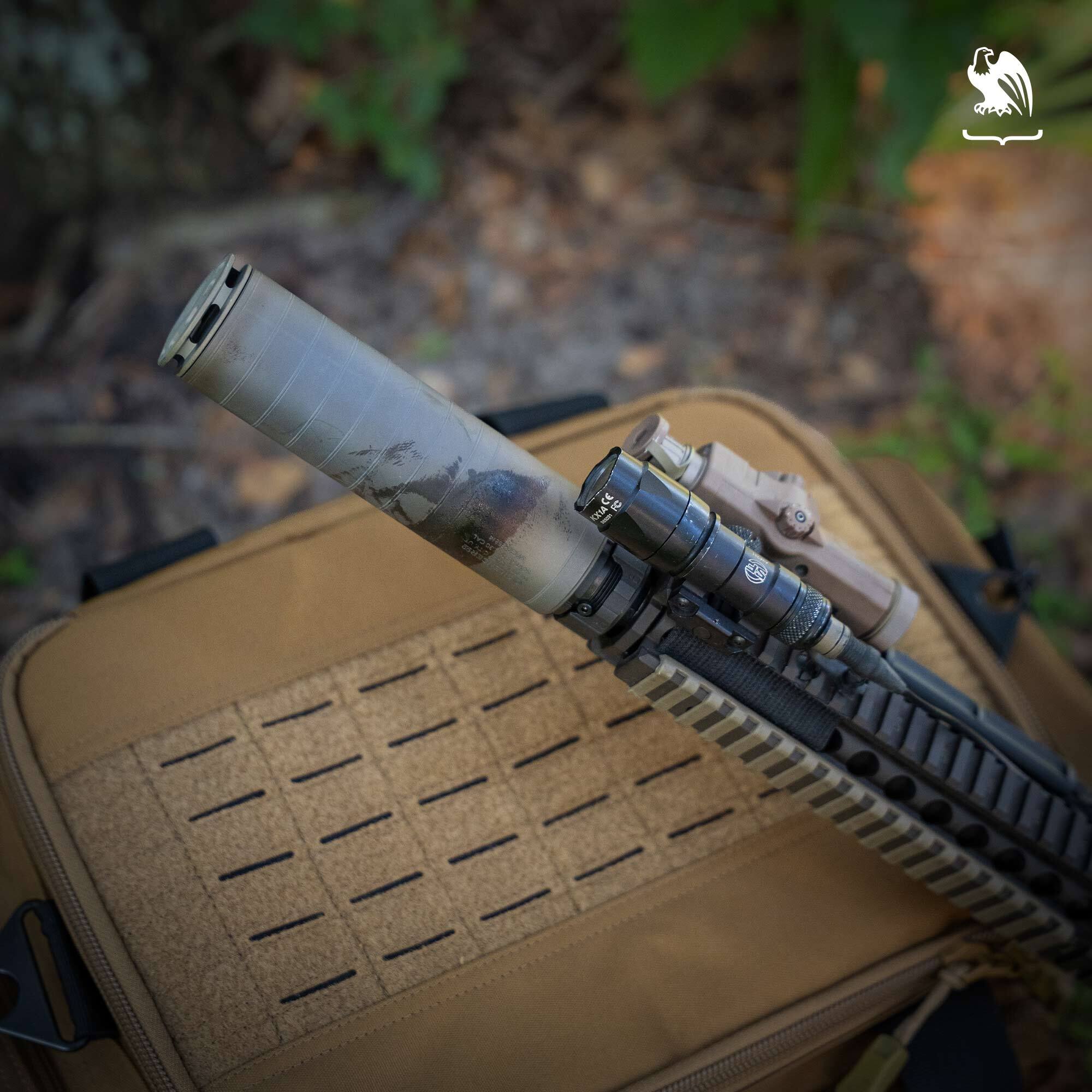 Suppressor A suppressor on a rifle sitting on top of a tan range bag